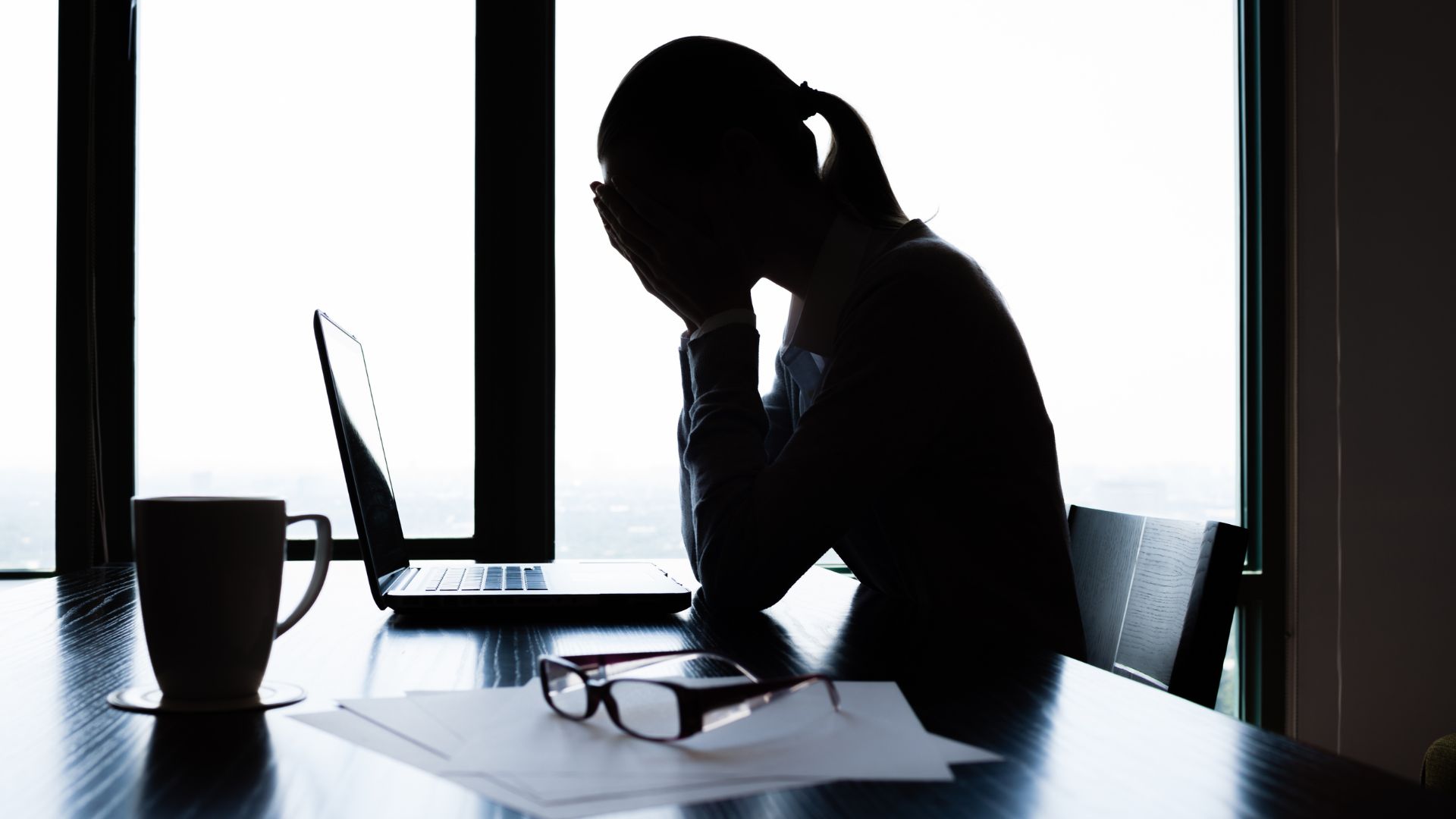 デスクで疲れ果てた女性のシルエット